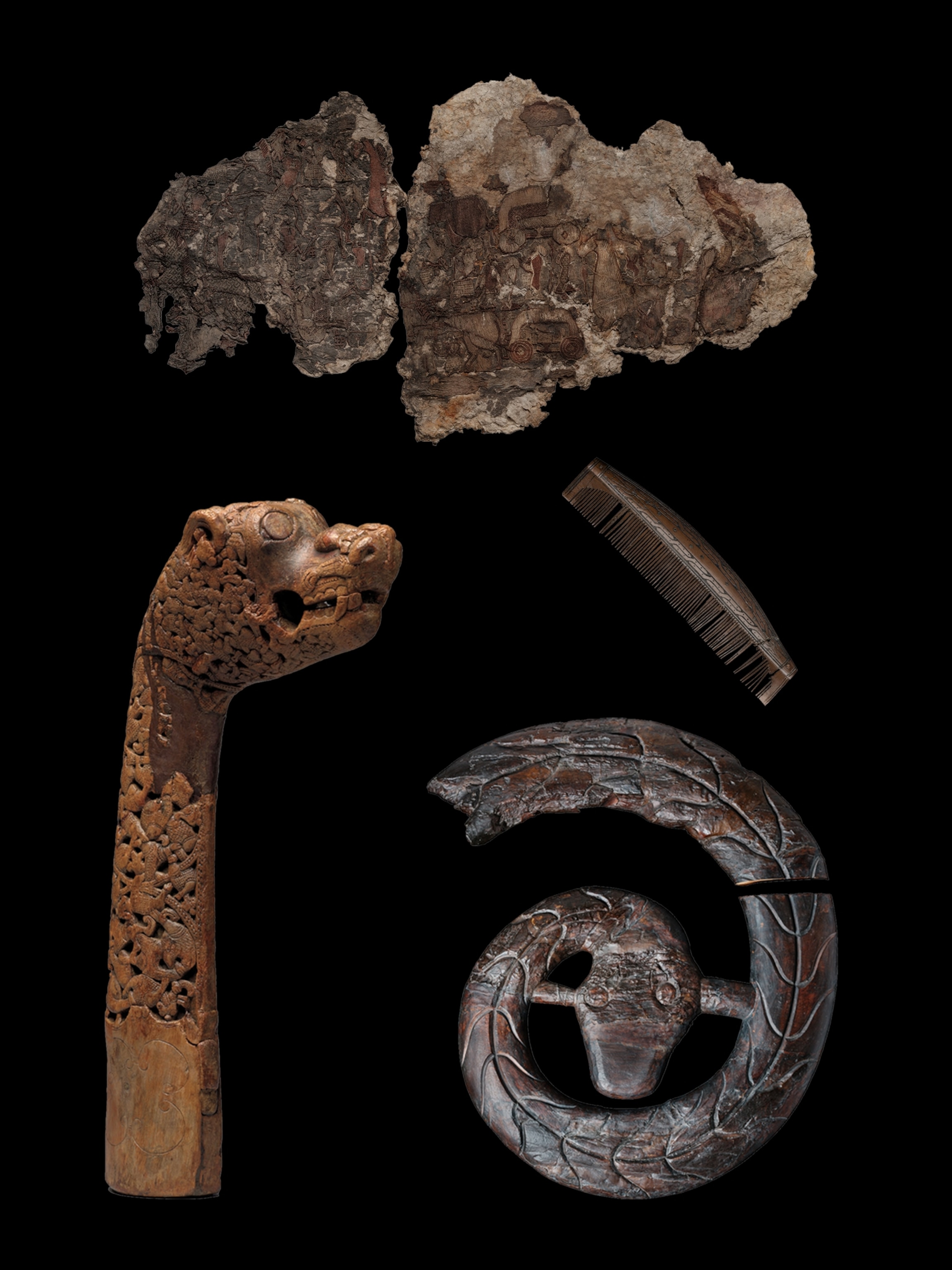 Viking artifacts on black: carved wooden animal head, a comb made from animal bone, a piece of tapestry and a wooden serpant